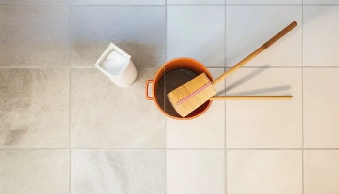 Applying vinegar solution to clean calcium buildup on shower floor